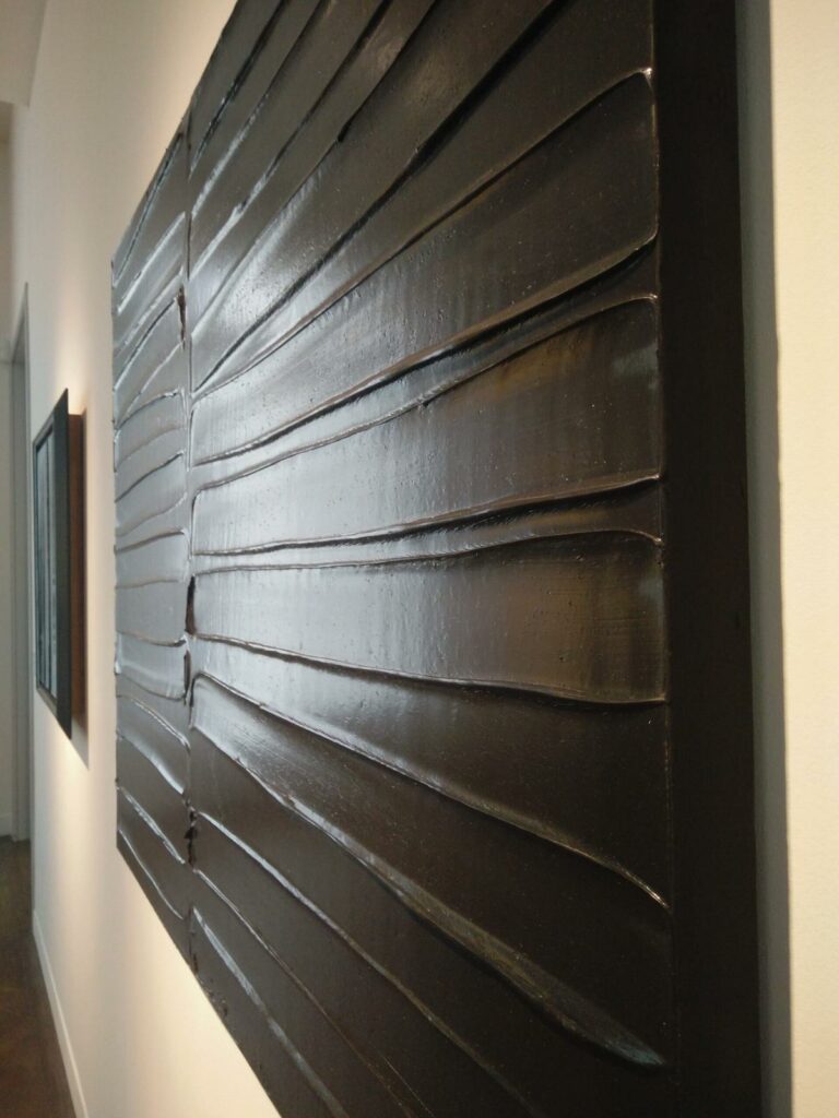 Vu en biais d'un tableau fait de traces noires permettant de voir le volume important de la peinture et les reflets blancs