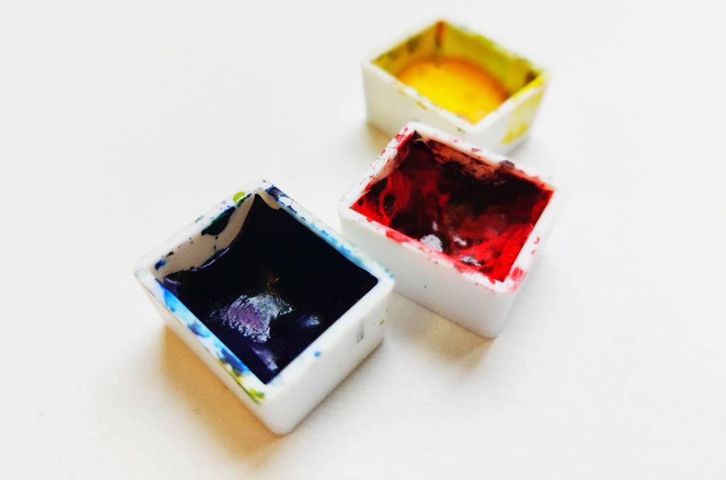 Trois godets d'aquarelle : bleu, rouge et jaune