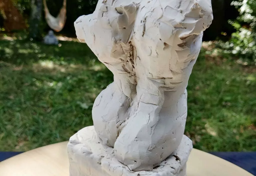 Gros plan sur une sculpture en argile où on devine un dos et des fesses