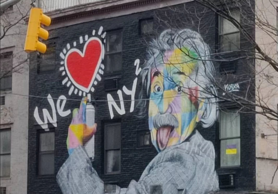 Graffiti s'étalant sur toute la façade d'un bâtiment de deux étages représentant Albert Einstein tirant la langue tagguant "We [cœur] NY²"