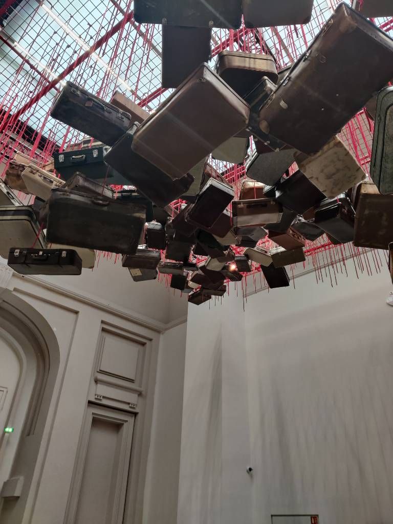 Des valises accrochées au plafond par un fil rouge vues du dessous