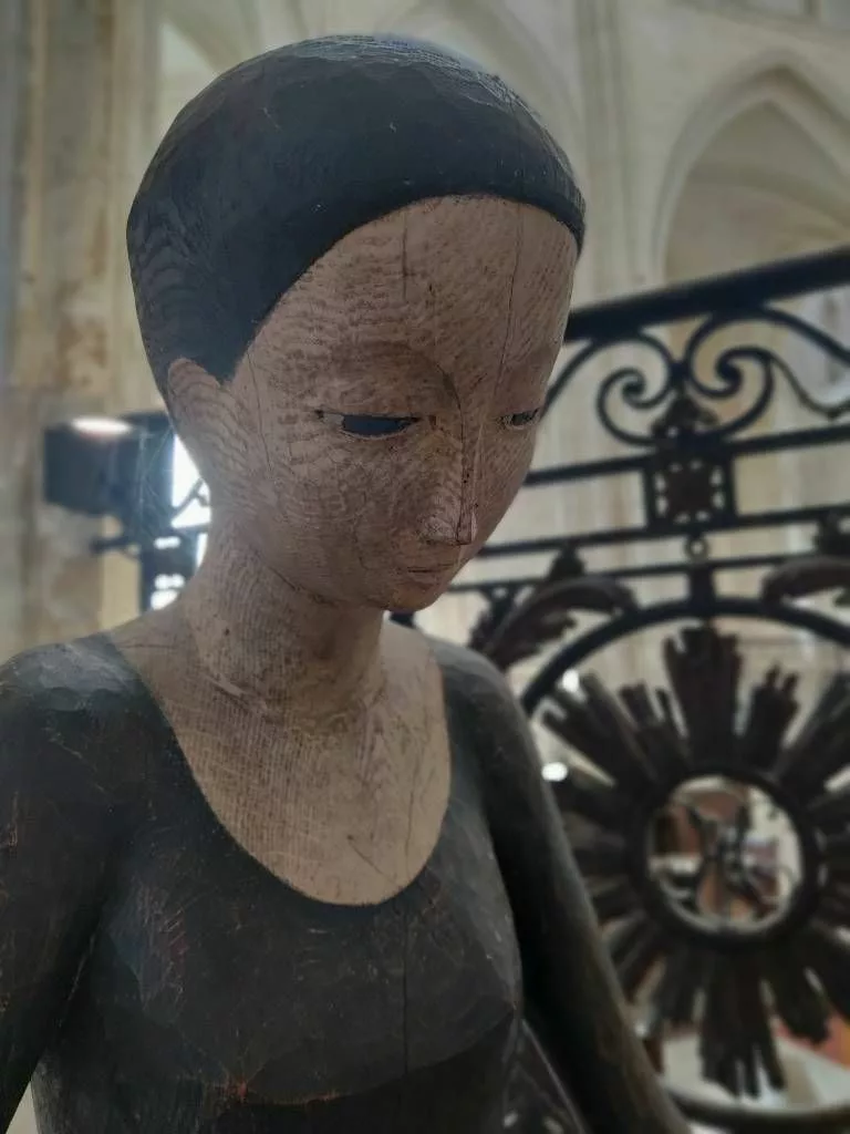 Gros plan sur une sculpture en bois représentant le visage d'une femme penchée