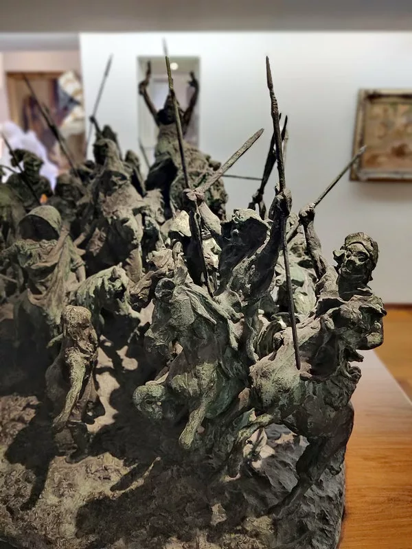 Détail d'une sculpture faite de personnages à cheval armes au poing, bras levés, dans une enchevêtrement