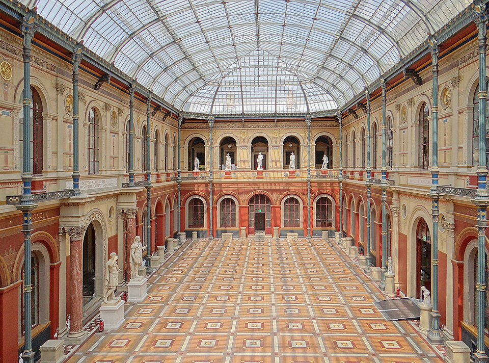 Grande cour intérieure recouverte d'une verrière avec des colonnades, des sculptures, des ornements architecturaux, etc.