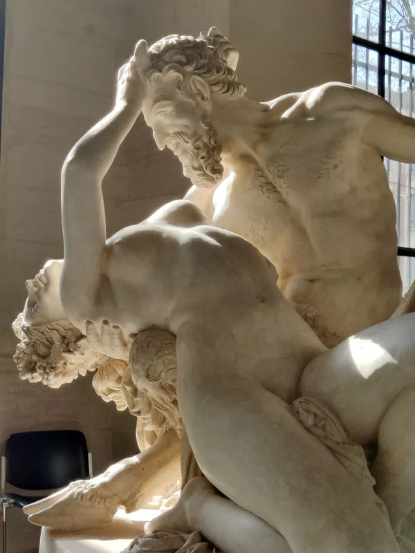Sculpture représentant un homme nu barbu tenant dans ses bras une femme nue à la renverse. On aperçoit les pieds de bouc de l'homme.