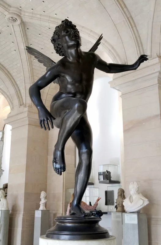 Sculpture d'un jeune garçon ailé qui lève une jambe dans un mouvement de douleur