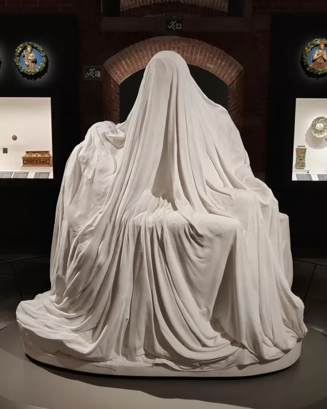 Sculpture laissant deviner des personnages sous un drap (mais les plus avertis reconnaissent la forme de la Piéta de Michel-Ange)