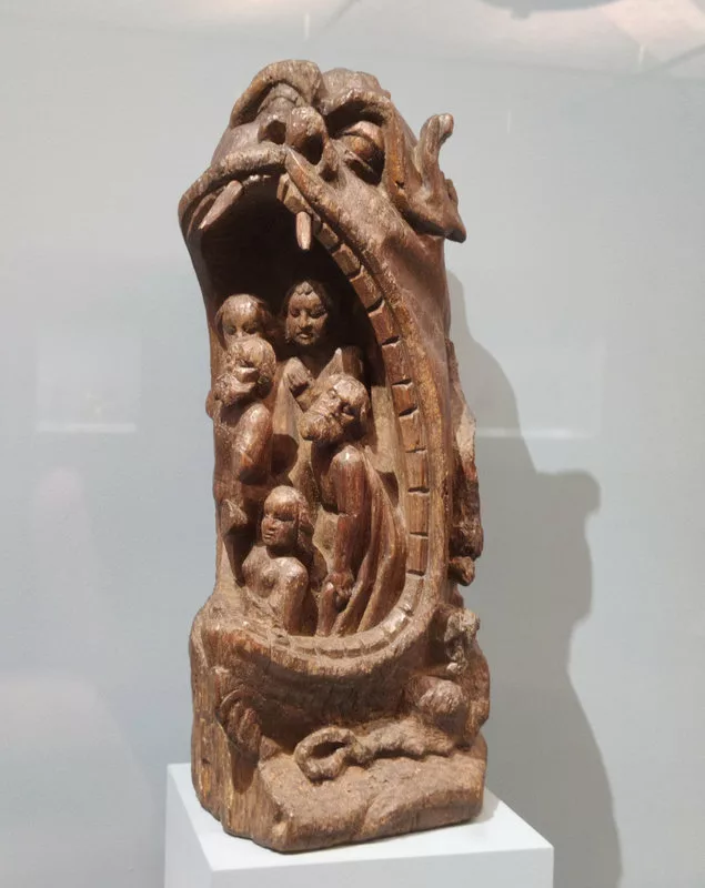 Sculpture en bois représentant des hommes et des femmes dans la gueule ouverte d'un monstre