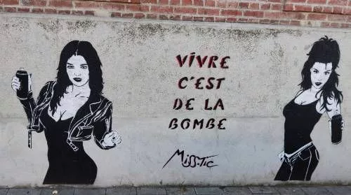 Tag au pochoir noir et blanc pour deux figures de femmes tenant des aérosols et noir et rouge pour le texte : "Vivre c'est de la bombe - Miss.Tic"