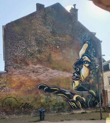 Sur une façade d'immeuble, un visage de profil qui souffle