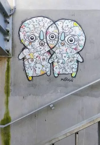 Deux petits personnages mignons globalement blancs mais avec plein de traces de couleurs et remplis de plein de petits personnages mignons "Moogli"