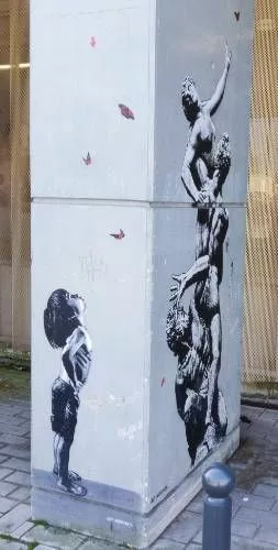 Une colonne de béton vue depuis la tranche permet de voir deux collages : un petit garçon tête levée vers des papillons et une reproduction de l'Enlèvement des Sabines