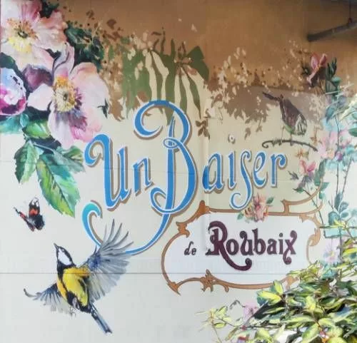 Peinture murale de fleurs, plantes, oiseaux et papillons avec le texte "Un Baiser de Roubaix"