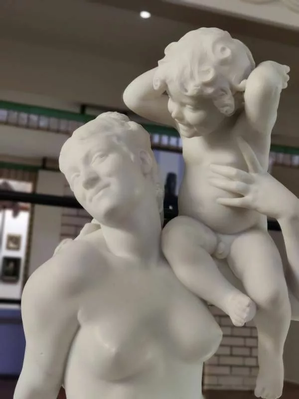 Sculpture représentant une femme souriant à son jeune enfant qui semble jouer avec elle