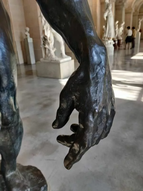 Vue d'un détail d'une sculpture : une main (sur le socle, un peu flou, on peut lire "A. Rodin")