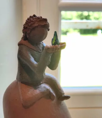 Petit personnage en terre cuite tenant dans ses mains une lumière