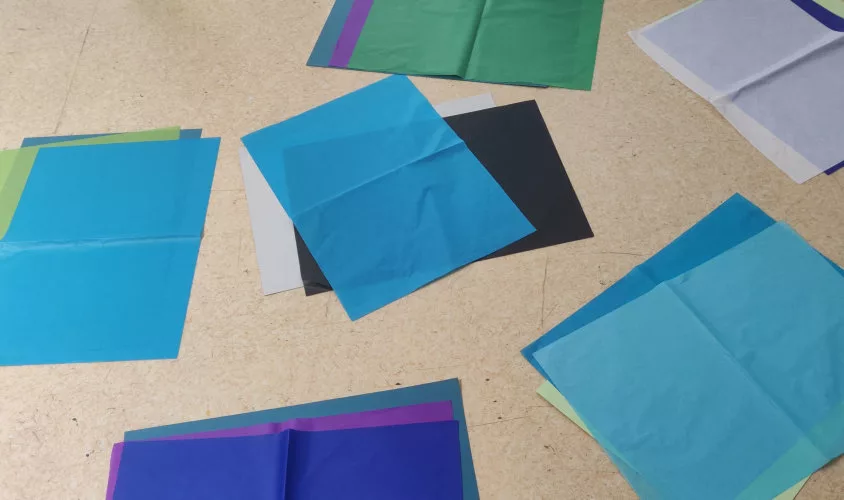 Un ensemble de papiers colorés posé au sol par groupe de trois couleurs