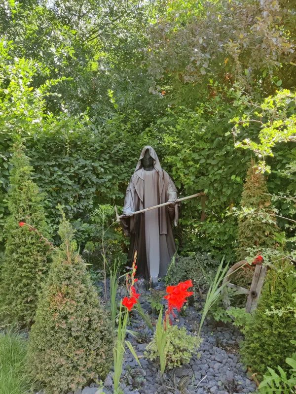 Une figure noire ressemblant à la mort dans un coin de jardin