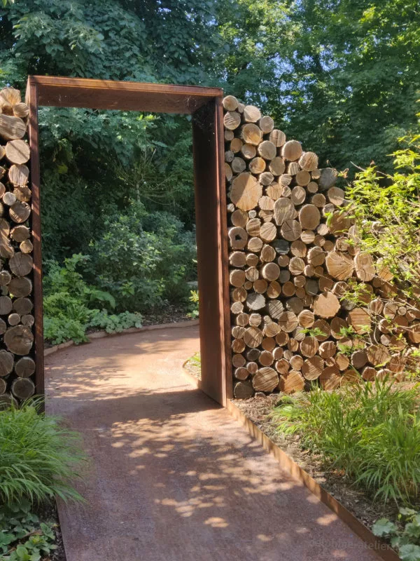 Une porte en métal flanquée de rondins de bois