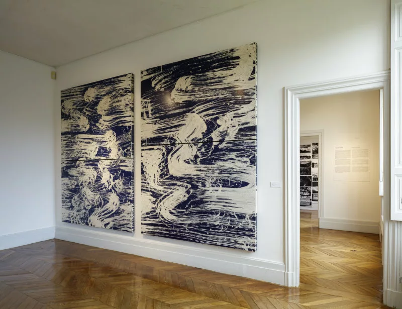 Deux tableaux sur lesquels des traces de peinture blanche en ligne sinueuses et dynamiques sur un fond bleu foncé