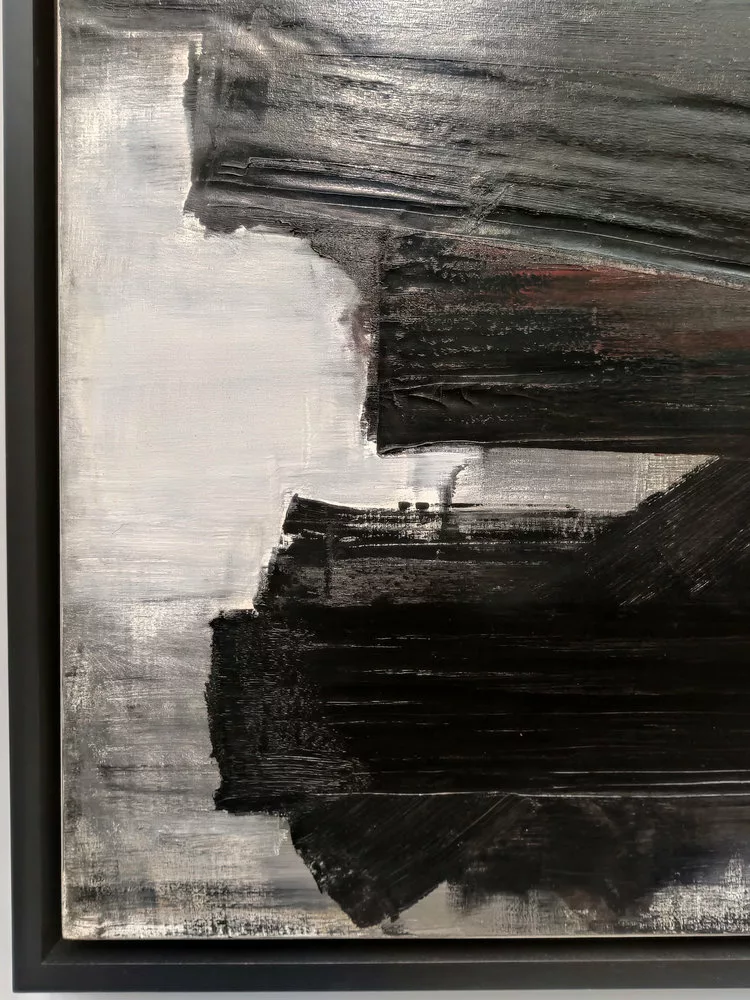 Des traces de peinture épaisses noir avec un soupçon de rouge à un endroit sur un fond pas tout à fait uni blanc, blanc-gris