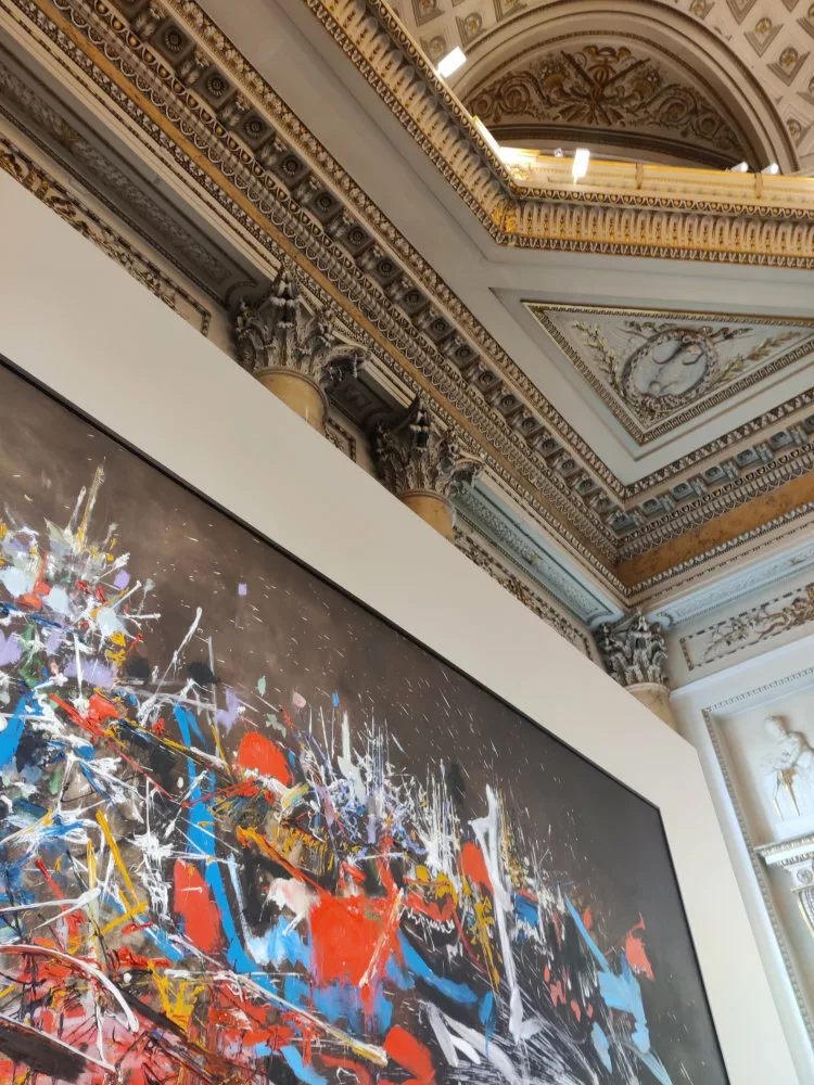 Vue d'une pièce dont on aperçoit un angle supérieur avec un décor de colonnes, d'ors, de voutes, etc. et un tableau moderne qui contraste