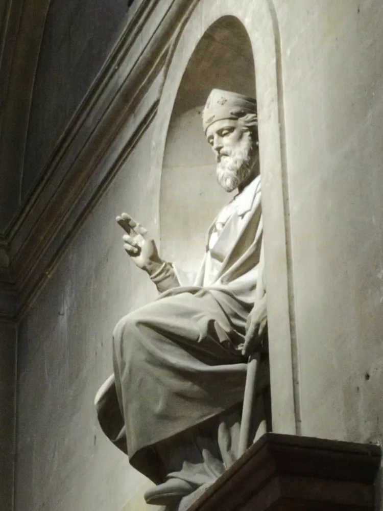 Une sculpture d'un homme assis bénissant prise de bas et de côté