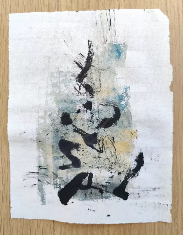 Une trace à l'encre noire qui pourrait ressembler à un idéogramme chinois et à la peinture dorée et bleue