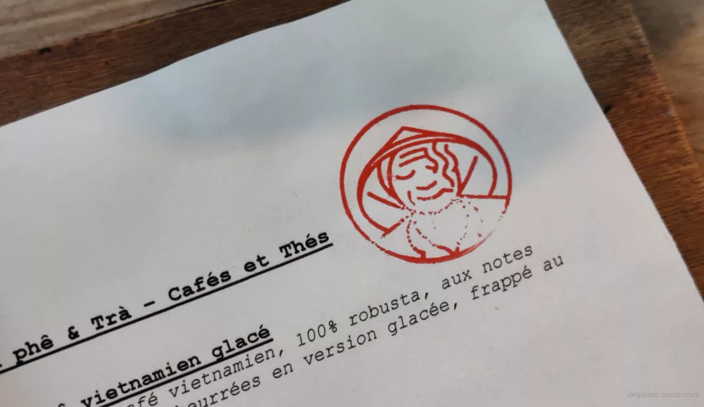 Une page de carte de restaurant avec un tampon représentant un visage avec un chapeau vietnamien