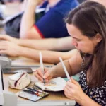 Moi, en train de dessiner et peindre dans un petit carnet lors d'une conférence