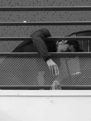 Une personne coincée derrière un grillage en train de faire un nœud