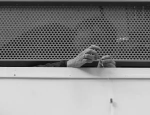 Une personne coincée derrière un grillage en train de faire un nœud