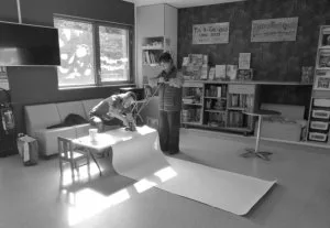 Deux personnes en train de fixer un système d'accrochage sur une grande fresque