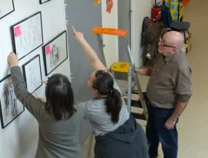 Des personnes en train d'accrocher et de commenter l'accrochage de tableaux