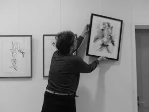 Une personne en train d'accrocher des tableaux