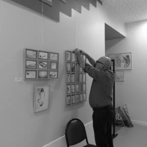 Une personne en train d'accrocher des tableaux