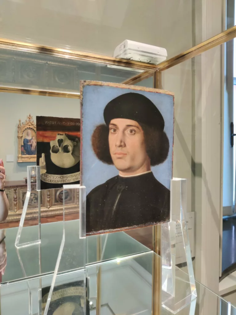 Portrait d'un jeune homme installé de sorte qu'on voit l'arrière dans un miroir : un crâne (à l'envers)