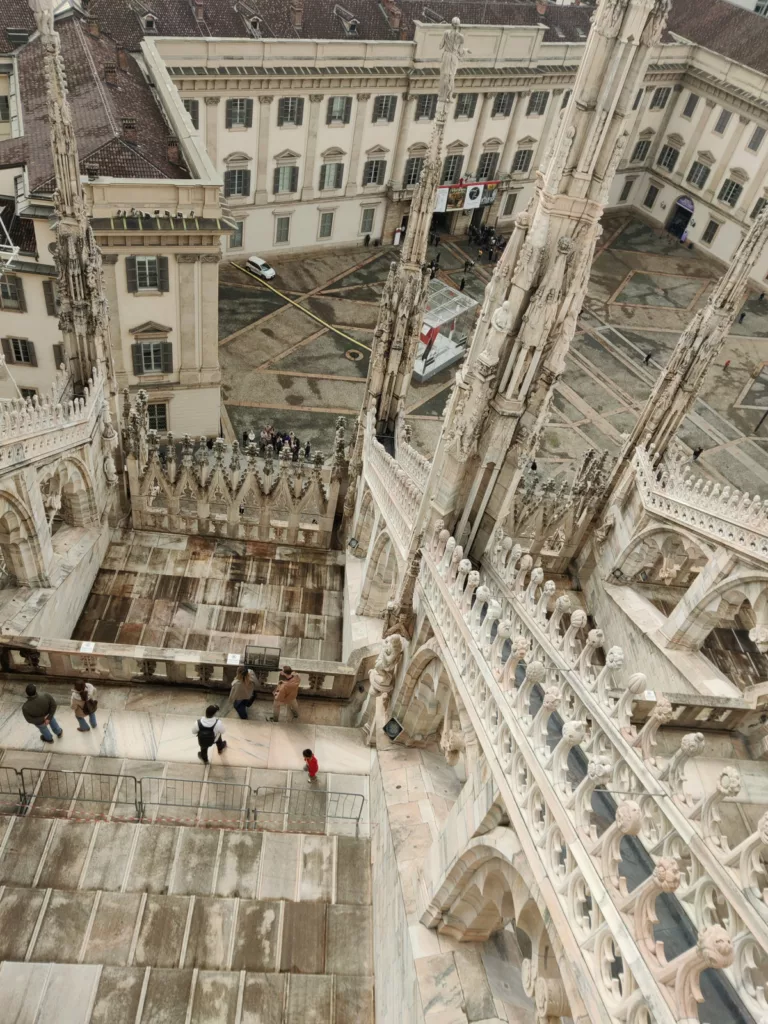 Vue en plongée sur une place avec de nombreux détails architecturaux (terrasses, ornements, tourelles)