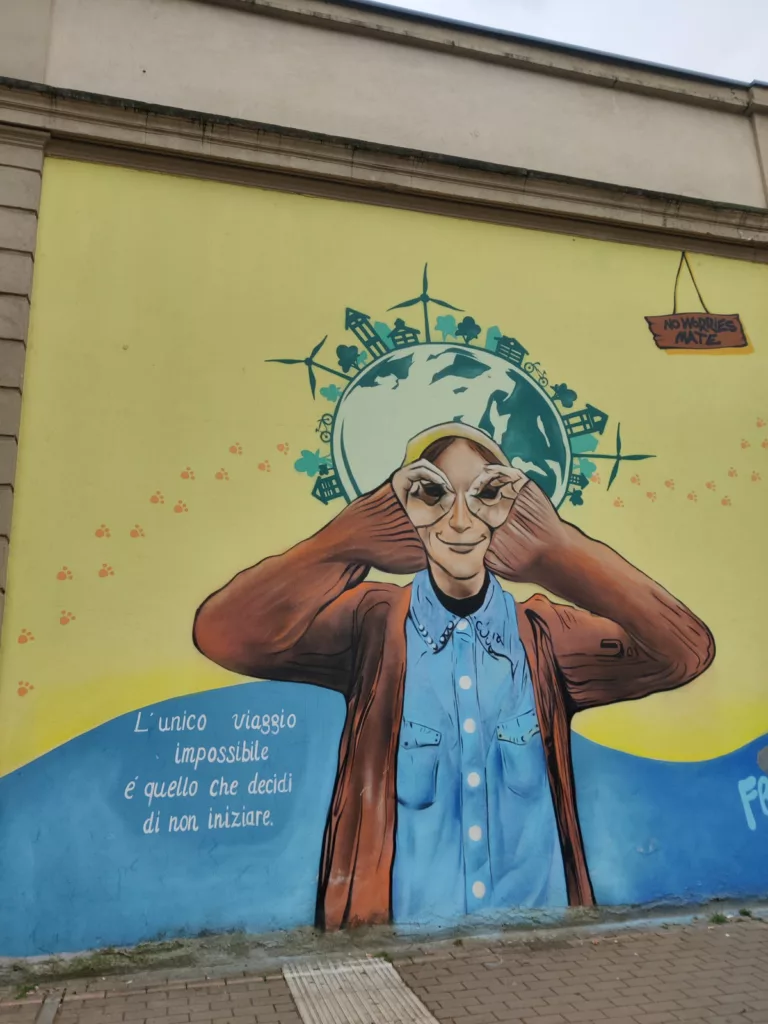 Œuvre de street art figurant une personne regardant à travers ses main avec l'inscription "L'unico viaggio impossibile é quello che decidi di non iniziare"