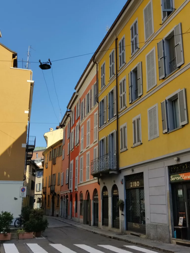 Une rue dont les bâtiments sont rouge, rose et jaune