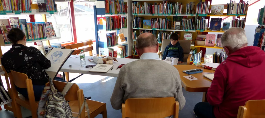 Trois dessinateurs en train de faire le portrait d'un enfant qui pose