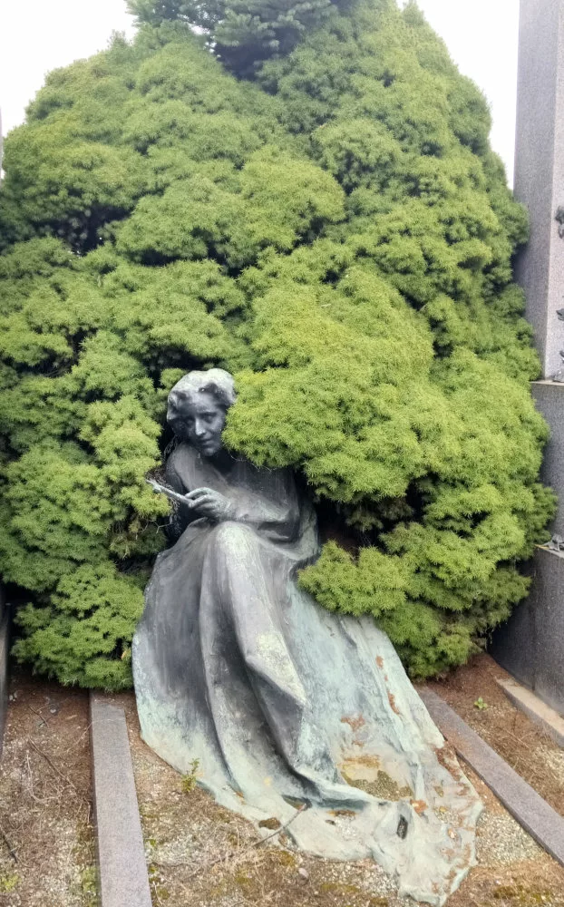 Tombe avec une sculpture d'une femme envahie par un nuage de végétation