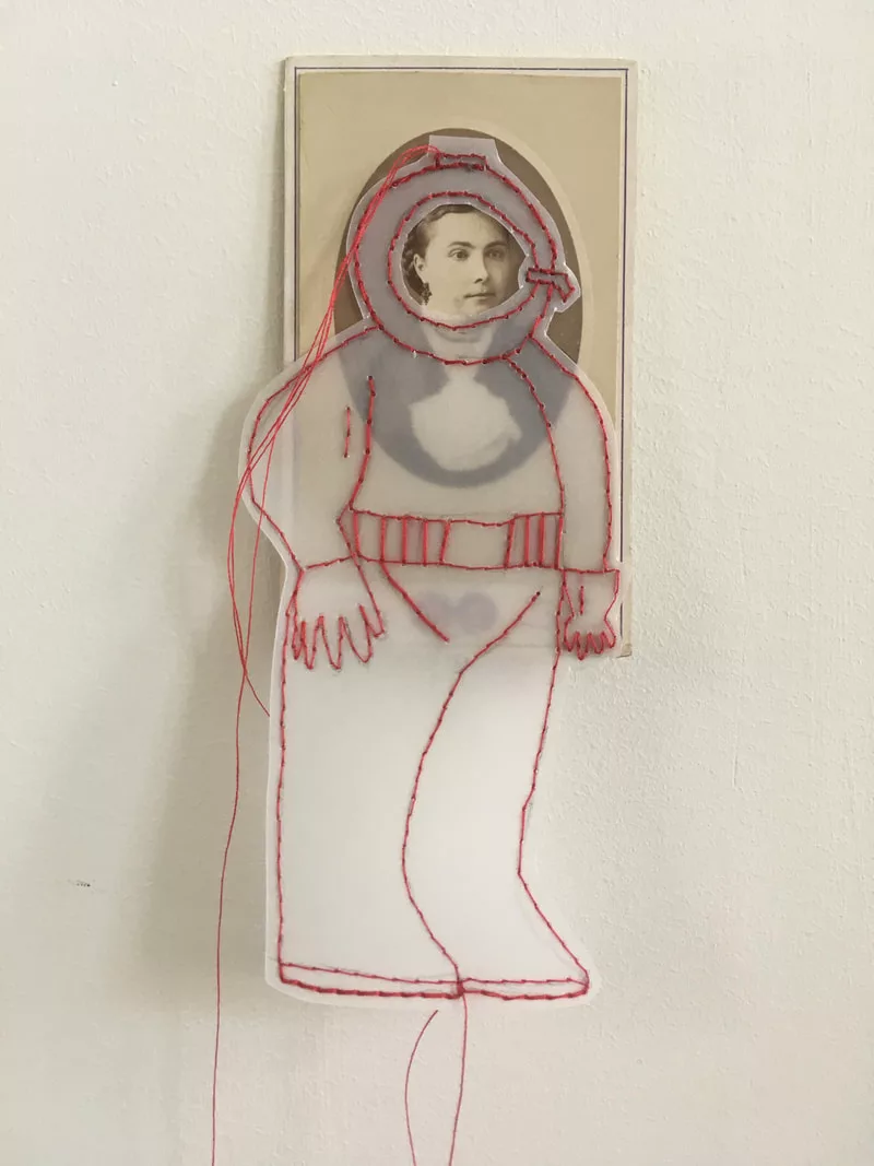 Un calque transparent en forme de cosmonaute est dessiné et cousu au fil rouge sur un portrait laissant apparaître le visage au niveau de la vitre du casque