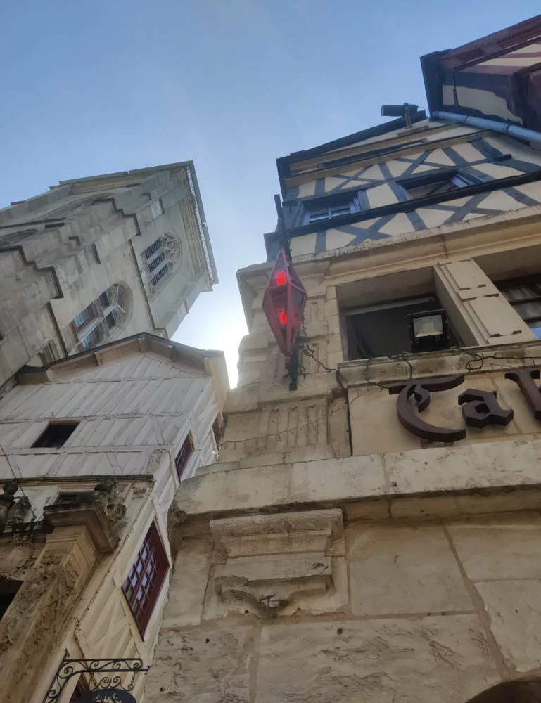 Vue en contre-plongée d'un bâtiment ancien avec une carotte (l'enseigne) en métal et en verre