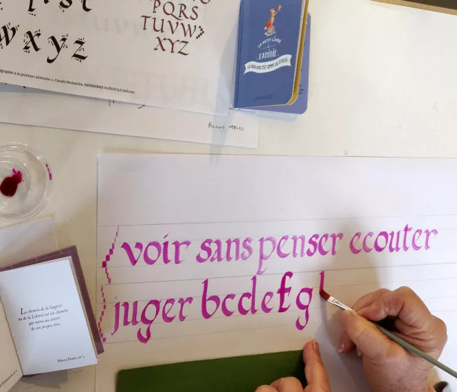 Un modèle d'écriture, du matériel et des mains en train de tracer des lettres