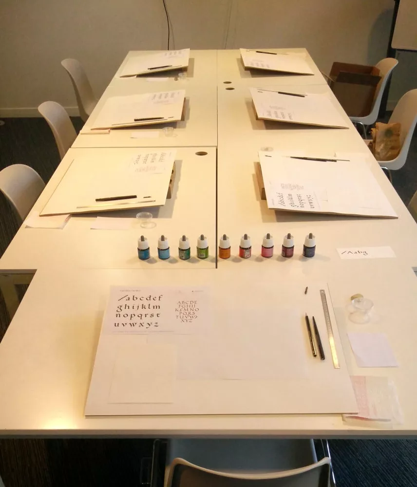 Table prête pour calligraphier : plan incliné, feuilles, encres, outils